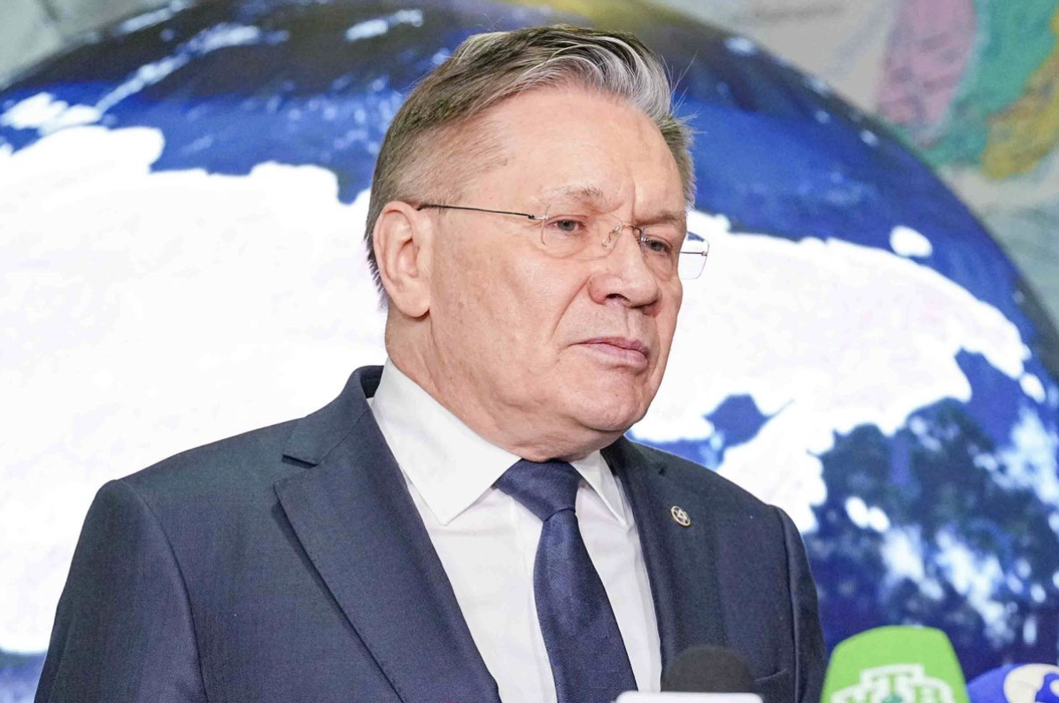 Executivo de terno concede entrevista diante de painel com mapa ao fundo, em contexto relacionado à cooperação internacional em energia nuclear.