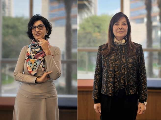 Duas mulheres aparecem em retratos lado a lado, em ambiente interno com janelas ao fundo. À esquerda, uma mulher usa vestido claro, óculos e lenço estampado colorido. À direita, outra mulher usa conjunto escuro estampado e posa de frente para a câmera.