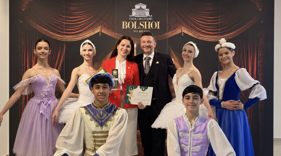 Representantes da Rosatom e da Escola do Teatro Bolshoi no Brasil posam ao lado de bailarinos durante cerimônia de renovação da parceria em Joinville