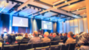 Público acompanha apresentação em auditório com telões, em imagem que representa debate profissional sobre tecnologia, vigilância digital e relações de trabalho